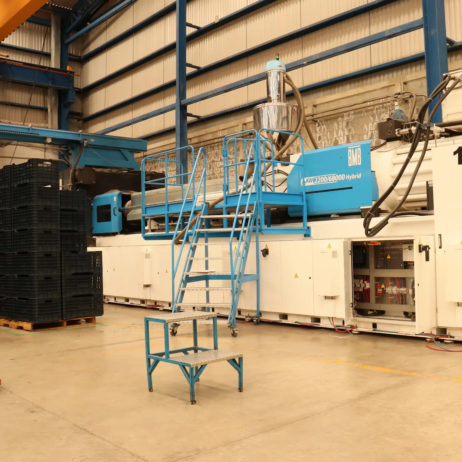 Máquina de inyección de la planta de Europlast junto a contenedores de plástico recién producidos